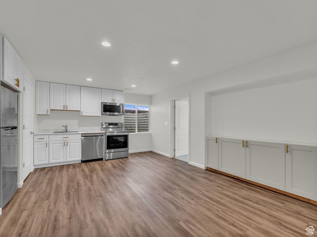 13249 S Shearing Cv, Herriman, UT 84096 - kitchen featuring appliances with stainless steel finishes, light wood-type flooring, light countertops, white cabinetry, and recessed lighting