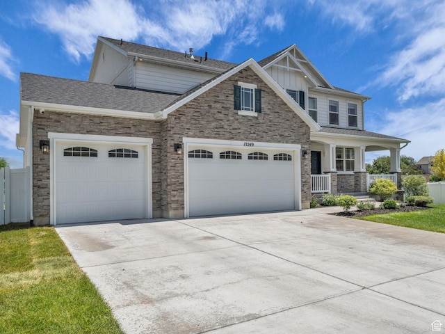 13249 S Shearing Cv, Herriman, UT 84096 - craftsman house featuring stone siding, covered porch, a garage, concrete driveway, and board and batten siding