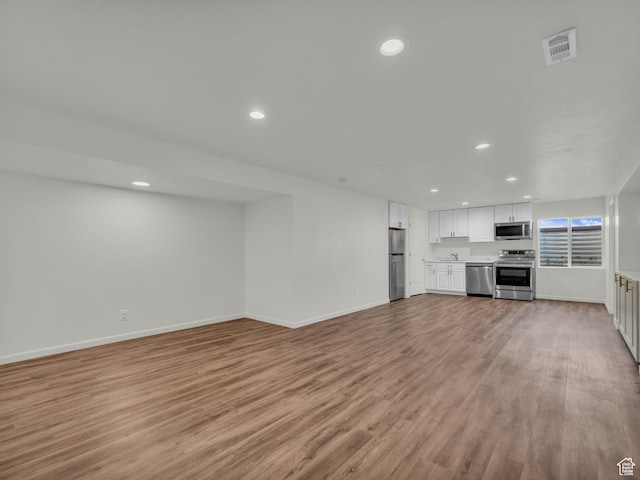 13249 S Shearing Cv, Herriman, UT 84096 - unfurnished living room with light wood-style flooring and recessed lighting