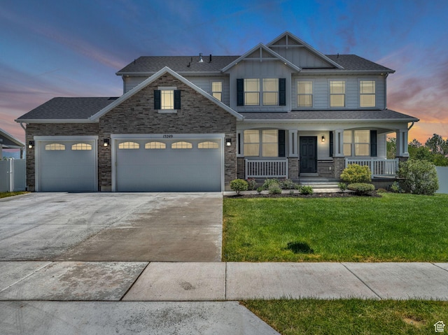 13249 S Shearing Cv, Herriman, UT 84096 - view of front of home featuring an attached garage, concrete driveway, a front yard, board and batten siding, and stone siding