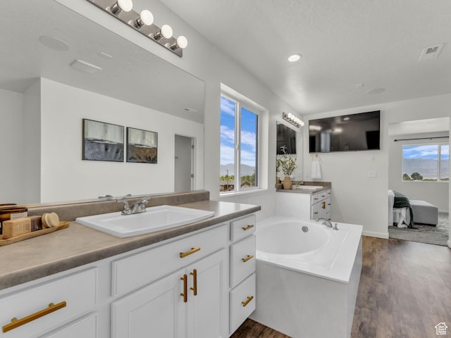 13249 S Shearing Cv, Herriman, UT 84096 - ensuite bathroom with two vanities, a bath, wood finished floors, and recessed lighting