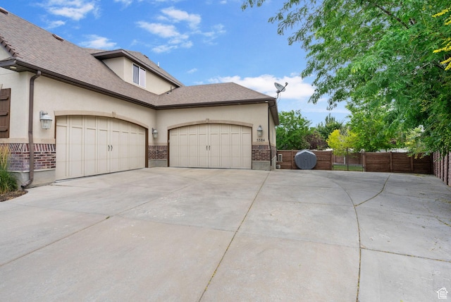 5584 N Gentle Breeze Ct, Stansbury Park, UT 84074 - view of home's exterior with driveway, stucco siding, a gate, and a garage