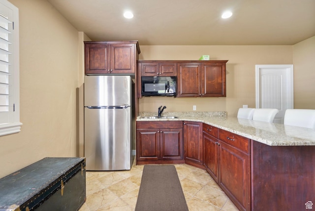 5584 N Gentle Breeze Ct, Stansbury Park, UT 84074 - kitchen with black microwave, freestanding refrigerator, a peninsula, light stone countertops, and recessed lighting