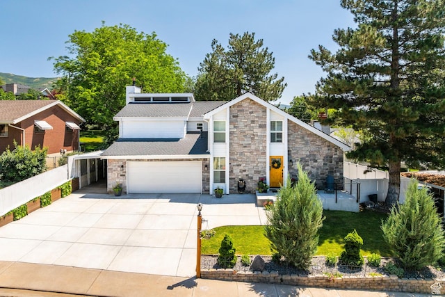 534 E 1400th St S, Bountiful, UT 84010 - mid-century inspired home featuring stone siding, concrete driveway, a chimney, roof mounted solar panels, and a shingled roof