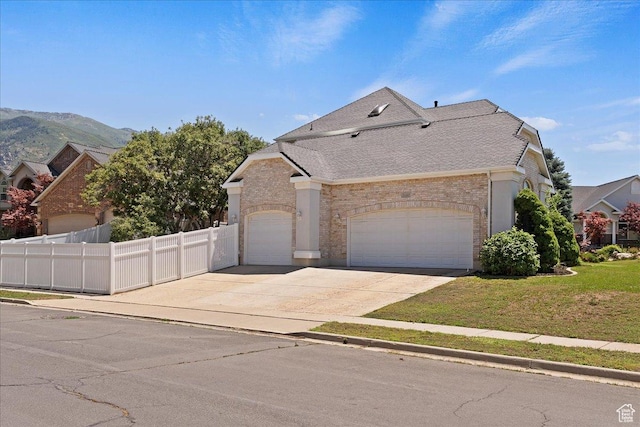 3680 N 2300 E, Layton, UT 84040 - french country style house with an attached garage, concrete driveway, brick siding, and a mountain view