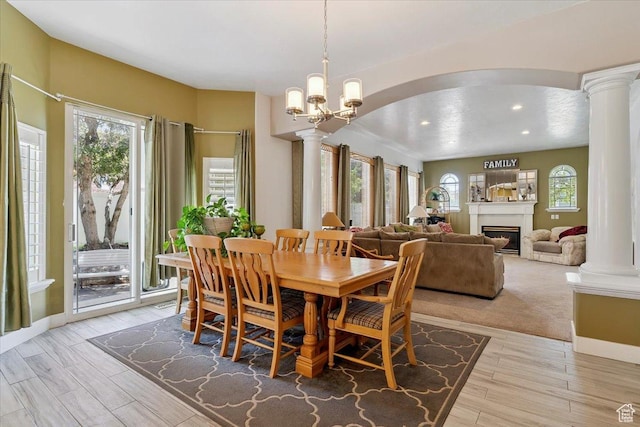 3680 N 2300 E, Layton, UT 84040 - dining room with decorative columns, arched walkways, a warm lit fireplace, light wood finished floors, and a chandelier