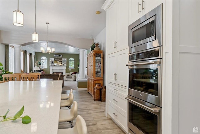 3680 N 2300 E, Layton, UT 84040 - kitchen with decorative columns, stainless steel appliances, arched walkways, light wood-type flooring, and white cabinets