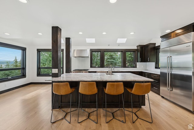 4670 Nelson Ct, Park City, UT 84098 - kitchen with stainless steel built in fridge, wall chimney exhaust hood, backsplash, a center island with sink, and a kitchen bar