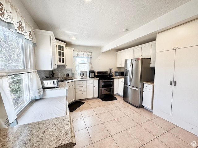 4606 W 5540 S, Kearns, UT 84118 - kitchen featuring appliances with stainless steel finishes, a textured ceiling, light countertops, light tile patterned flooring, and glass insert cabinets