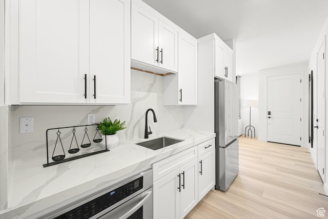 578 S Cecita Way Unit 91, St George, UT 84770 - kitchen with appliances with stainless steel finishes, white cabinetry, light stone countertops, and light wood-type flooring