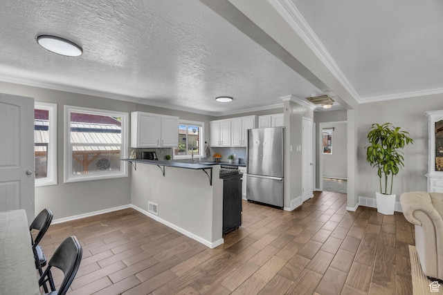 4682 S 475 W, Washington Terrace, UT 84405 - kitchen with freestanding refrigerator, dark countertops, a peninsula, white cabinetry, and a kitchen breakfast bar