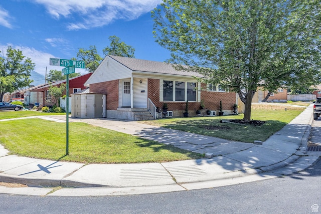 4682 S 475 W, Washington Terrace, UT 84405 - view of front facade featuring brick siding, a front yard, concrete driveway, and a storage unit