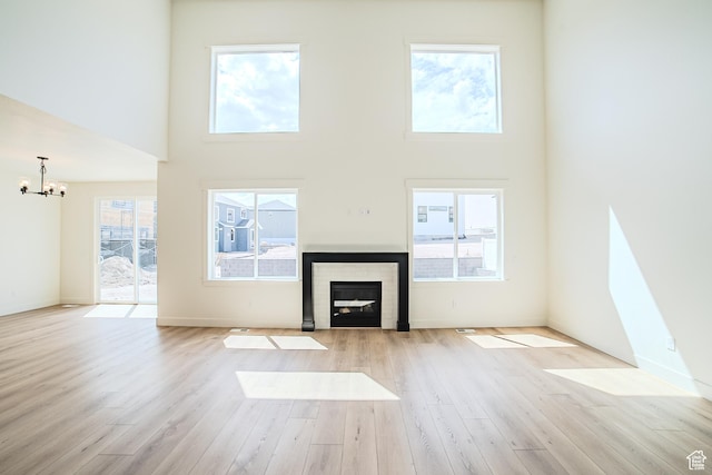 10942 S Samoa Dune Dr, South Jordan, UT 84009 - unfurnished living room with a chandelier, light wood-style flooring, a towering ceiling, and a fireplace