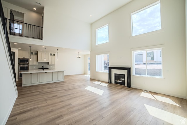 10942 S Samoa Dune Dr, South Jordan, UT 84009 - unfurnished living room featuring a high ceiling, light wood-type flooring, a tile fireplace, and recessed lighting