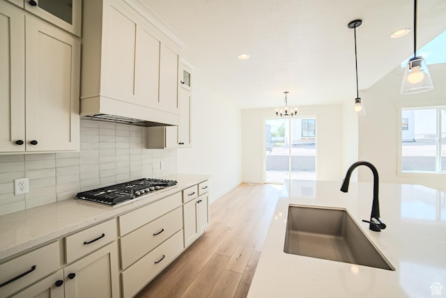 10942 S Samoa Dune Dr, South Jordan, UT 84009 - kitchen with stainless steel gas cooktop, light wood finished floors, a chandelier, backsplash, and pendant lighting