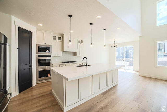 10942 S Samoa Dune Dr, South Jordan, UT 84009 - kitchen featuring stainless steel appliances, light wood-type flooring, light countertops, glass insert cabinets, and a center island with sink