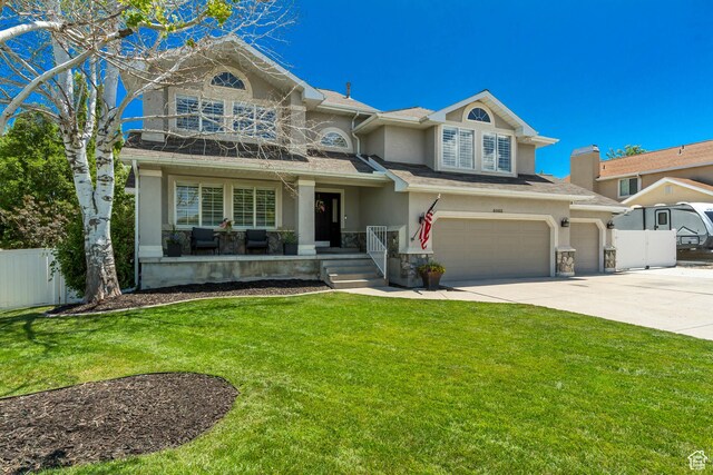 6063 S Kamas Dr W, Taylorsville, UT 84129 - view of front of house with stucco siding, concrete driveway, an attached garage, a balcony, and covered porch