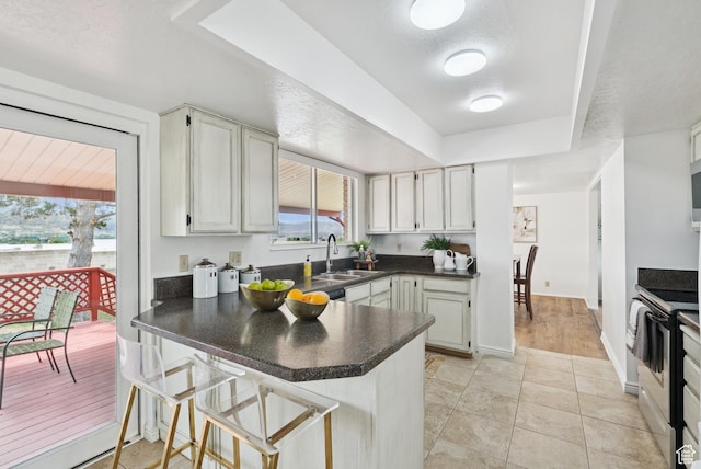 1074 E Spring Ridge Dr, Sandy, UT 84094 - kitchen with stainless steel electric range oven, a peninsula, dark countertops, a tray ceiling, and healthy amount of natural light