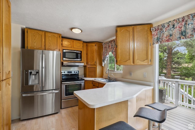 601 E Hilo St S, Sandy, UT 84070 - kitchen with appliances with stainless steel finishes, light countertops, a peninsula, light wood-type flooring, and under cabinet range hood