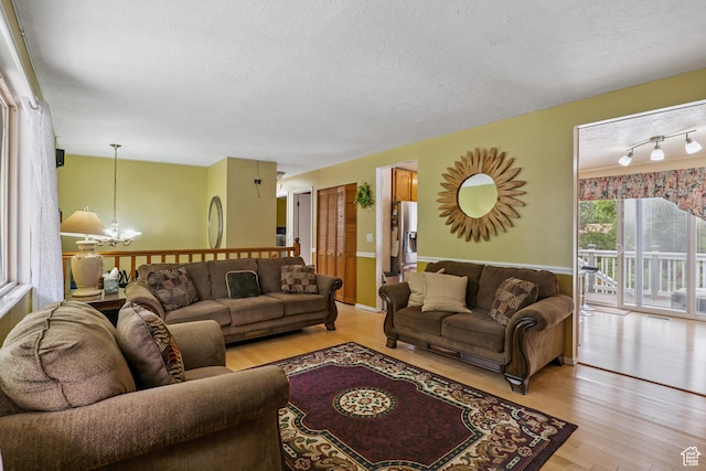 601 E Hilo St S, Sandy, UT 84070 - living room with light wood-type flooring, a textured ceiling, and a chandelier