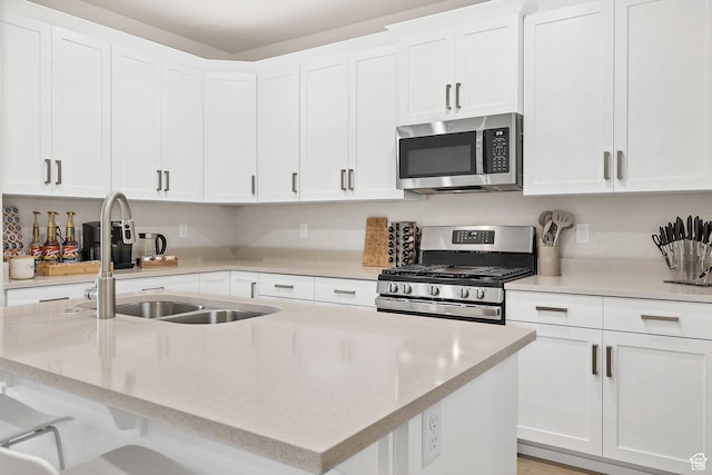 1210 N Mistico Aly, Washington, UT 84780 - kitchen with appliances with stainless steel finishes, a kitchen island with sink, white cabinetry, light stone countertops, and a breakfast bar area
