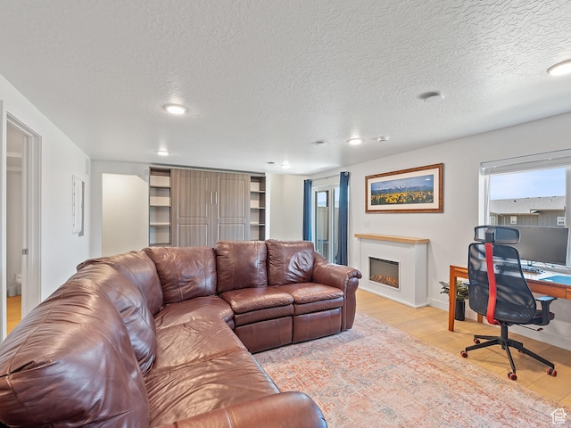 2309 N Wildwood Ln, Heber City, UT 84032 - living room with light wood-style floors, a lit fireplace, a textured ceiling, recessed lighting, and a desk