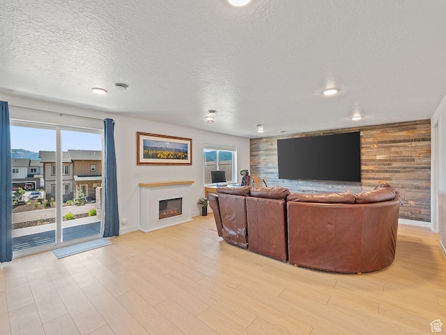 2309 N Wildwood Ln, Heber City, UT 84032 - living room featuring a glass covered fireplace, healthy amount of natural light, wood walls, light wood finished floors, and a textured ceiling