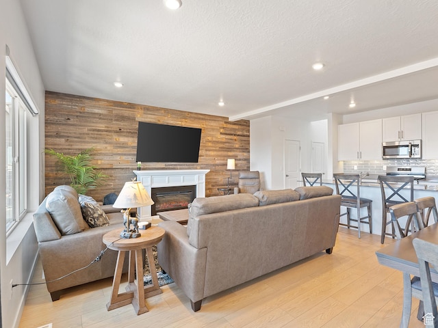 2309 N Wildwood Ln, Heber City, UT 84032 - living area featuring wood walls, light wood finished floors, recessed lighting, a glass covered fireplace, and a textured ceiling