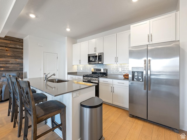 2309 N Wildwood Ln, Heber City, UT 84032 - kitchen featuring appliances with stainless steel finishes, dark countertops, light wood-type flooring, a breakfast bar, and backsplash