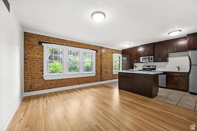 555 E 100 S Unit 303, Salt Lake City, UT 84102 - kitchen featuring stainless steel appliances, brick wall, light countertops, a center island, and a textured ceiling