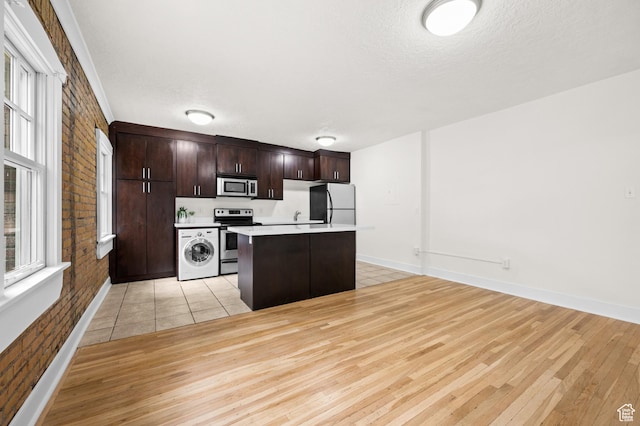 555 E 100 S Unit 303, Salt Lake City, UT 84102 - kitchen featuring stainless steel appliances, washer / clothes dryer, light wood-style floors, dark brown cabinets, and a textured ceiling