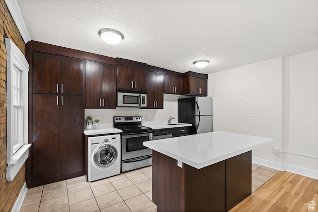 555 E 100 S Unit 303, Salt Lake City, UT 84102 - kitchen with stainless steel appliances, washer / clothes dryer, light countertops, dark brown cabinets, and a center island