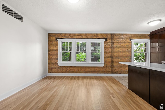 555 E 100 S Unit 303, Salt Lake City, UT 84102 - unfurnished living room featuring brick wall, a textured ceiling, and light wood-style floors