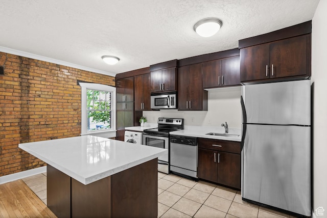 555 E 100 S Unit 303, Salt Lake City, UT 84102 - kitchen with appliances with stainless steel finishes, brick wall, light countertops, dark brown cabinetry, and a kitchen island