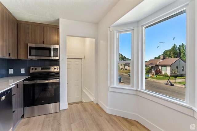 178 Country Club Dr, South Ogden, UT 84405 - kitchen with stainless steel appliances, light wood-style flooring, decorative backsplash, light countertops, and brown cabinetry