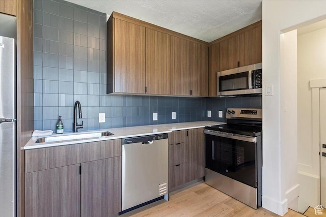 178 Country Club Dr, South Ogden, UT 84405 - kitchen with stainless steel appliances, light countertops, tasteful backsplash, light wood-style floors, and modern cabinets