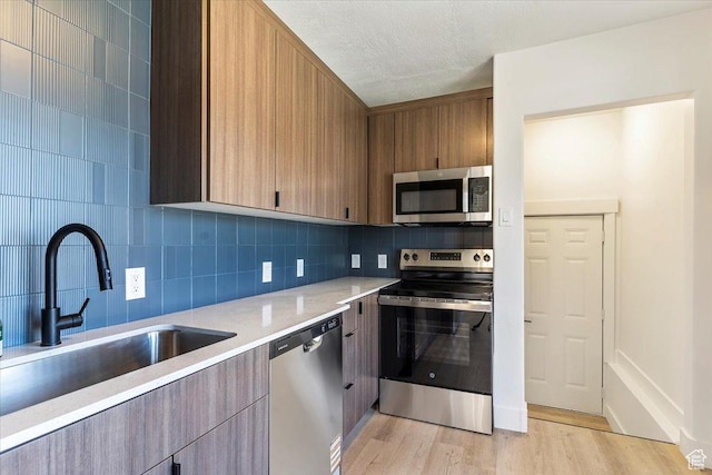 178 Country Club Dr, South Ogden, UT 84405 - kitchen featuring appliances with stainless steel finishes, light countertops, decorative backsplash, light wood-style flooring, and modern cabinets