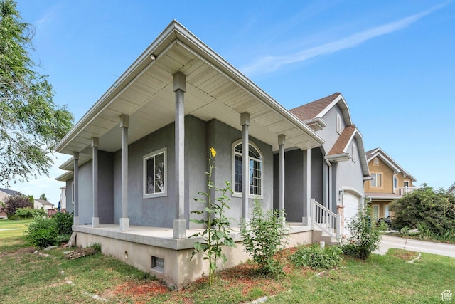 1430 S Heather Ln, Syracuse, UT 84075 - view of side of home featuring stucco siding, covered porch, concrete driveway, and a lawn