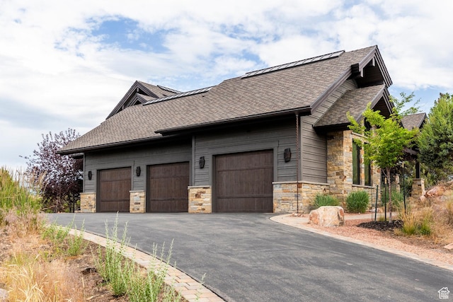 223 N Ibapah Peak Dr, Heber City, UT 84032 - view of side of home featuring stone siding, roof with shingles, an attached garage, and asphalt driveway