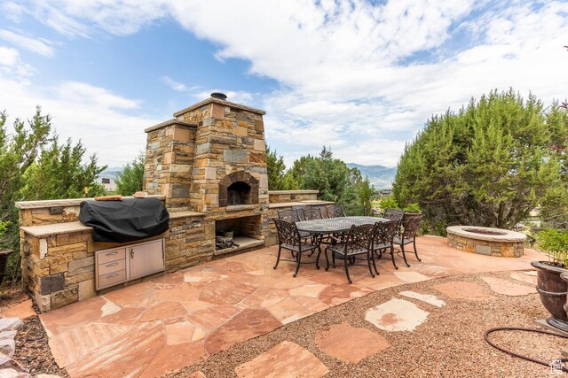 223 N Ibapah Peak Dr, Heber City, UT 84032 - view of patio / terrace with an outdoor fire pit, an outdoor stone fireplace, an outdoor kitchen, a mountain view, and outdoor dining space