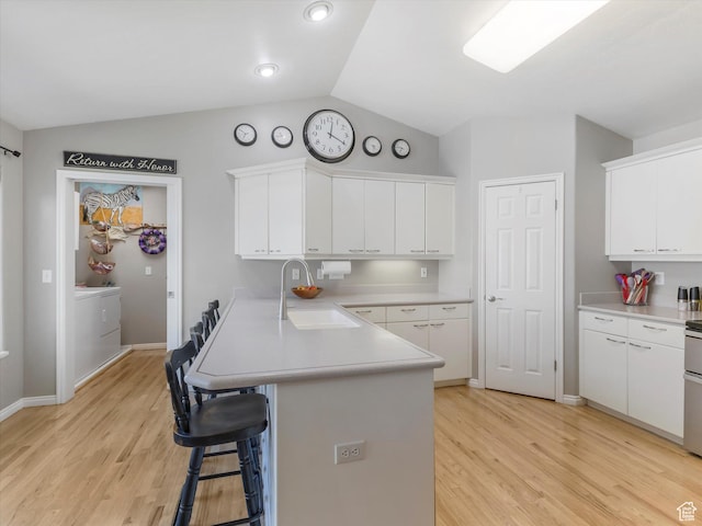 2287 N 470 E, Provo, UT 84604 - kitchen featuring a peninsula, lofted ceiling, light wood-style flooring, a breakfast bar area, and light countertops