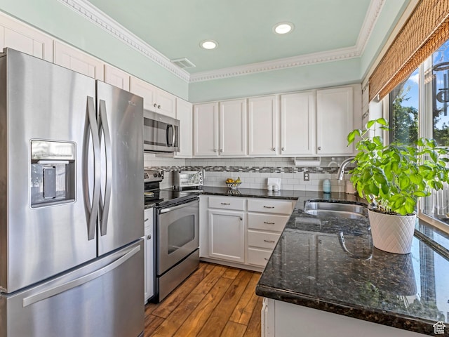 4856 S 1690 E # 88, Salt Lake City, UT 84117 - kitchen featuring stainless steel appliances, white cabinetry, ornamental molding, dark stone counters, and decorative backsplash