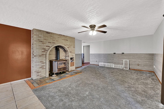 5577 W 4000 S, Hooper, UT 84315 - unfurnished living room featuring a wood stove, ceiling fan, a textured ceiling, tile patterned flooring, and wainscoting