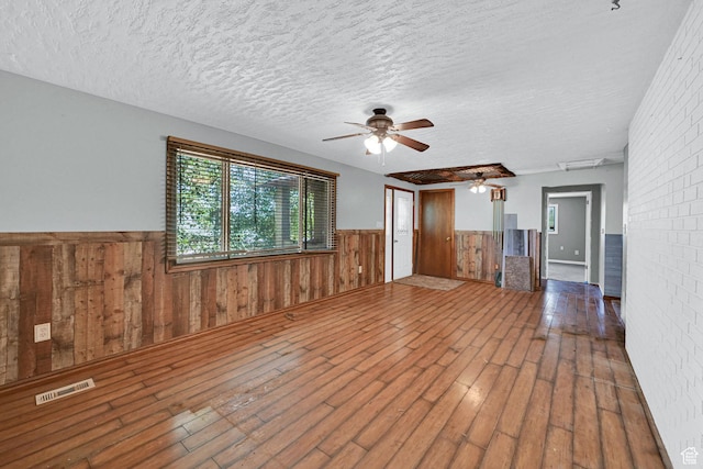 5577 W 4000 S, Hooper, UT 84315 - empty room featuring a wainscoted wall, a ceiling fan, hardwood / wood-style flooring, a textured ceiling, and wood walls