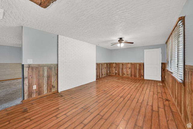 5577 W 4000 S, Hooper, UT 84315 - empty room featuring ceiling fan, a textured ceiling, wainscoting, wood finished floors, and wood walls