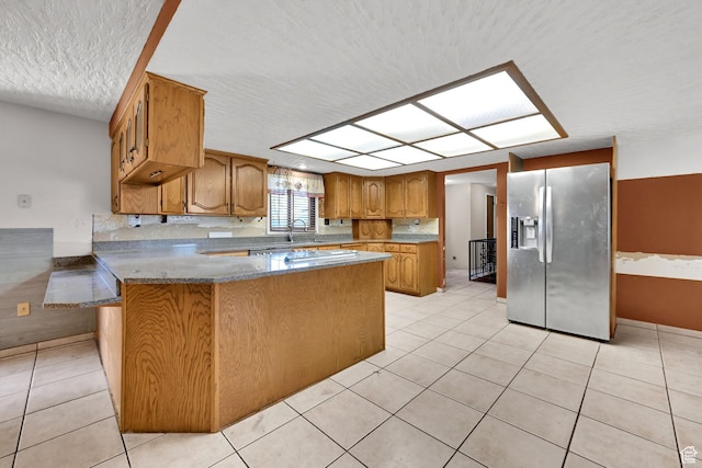 5577 W 4000 S, Hooper, UT 84315 - kitchen featuring stainless steel refrigerator with ice dispenser, a peninsula, a textured ceiling, brown cabinetry, and light tile patterned flooring