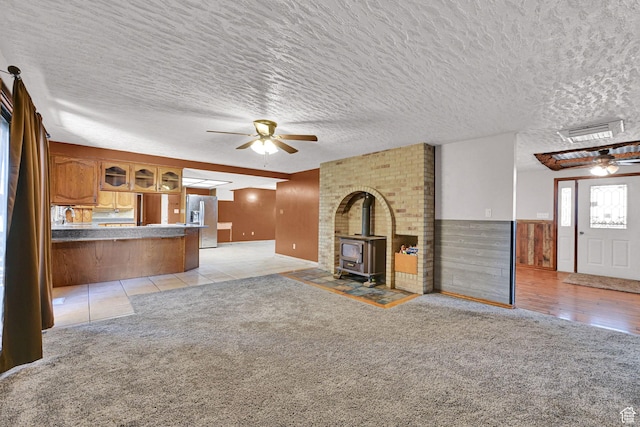 5577 W 4000 S, Hooper, UT 84315 - unfurnished living room featuring a ceiling fan, a wood stove, a textured ceiling, light carpet, and wainscoting