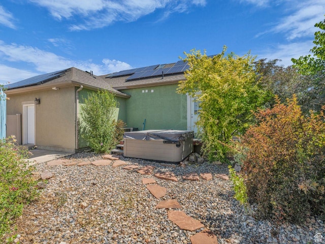 8503 S Spiral Jetty Cir W Unit 2083, West Jordan, UT 84081 - view of property exterior with a hot tub, roof mounted solar panels, stucco siding, and roof with shingles