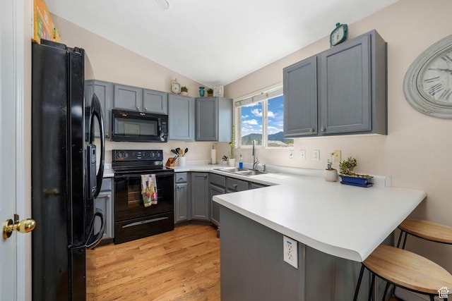 3142 S Sugar Bowl Ln, West Valley City, UT 84128 - kitchen with black appliances, a peninsula, gray cabinetry, a breakfast bar area, and lofted ceiling