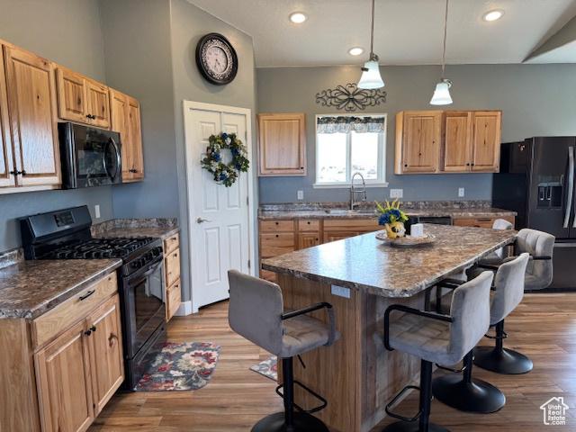 4058 E 5000 S, Vernal, UT 84078 - kitchen featuring black appliances, a breakfast bar, a kitchen island, recessed lighting, and wood finished floors